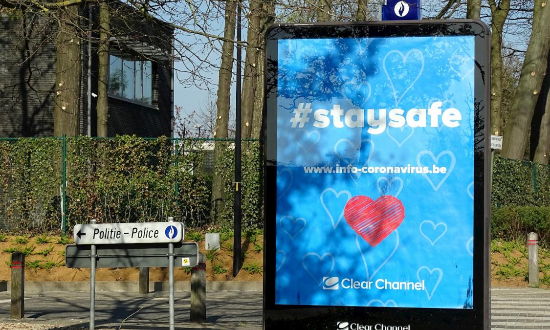 Straatbeeld met informatiebord sensibiliseringscampagne Stay Safe overheid.